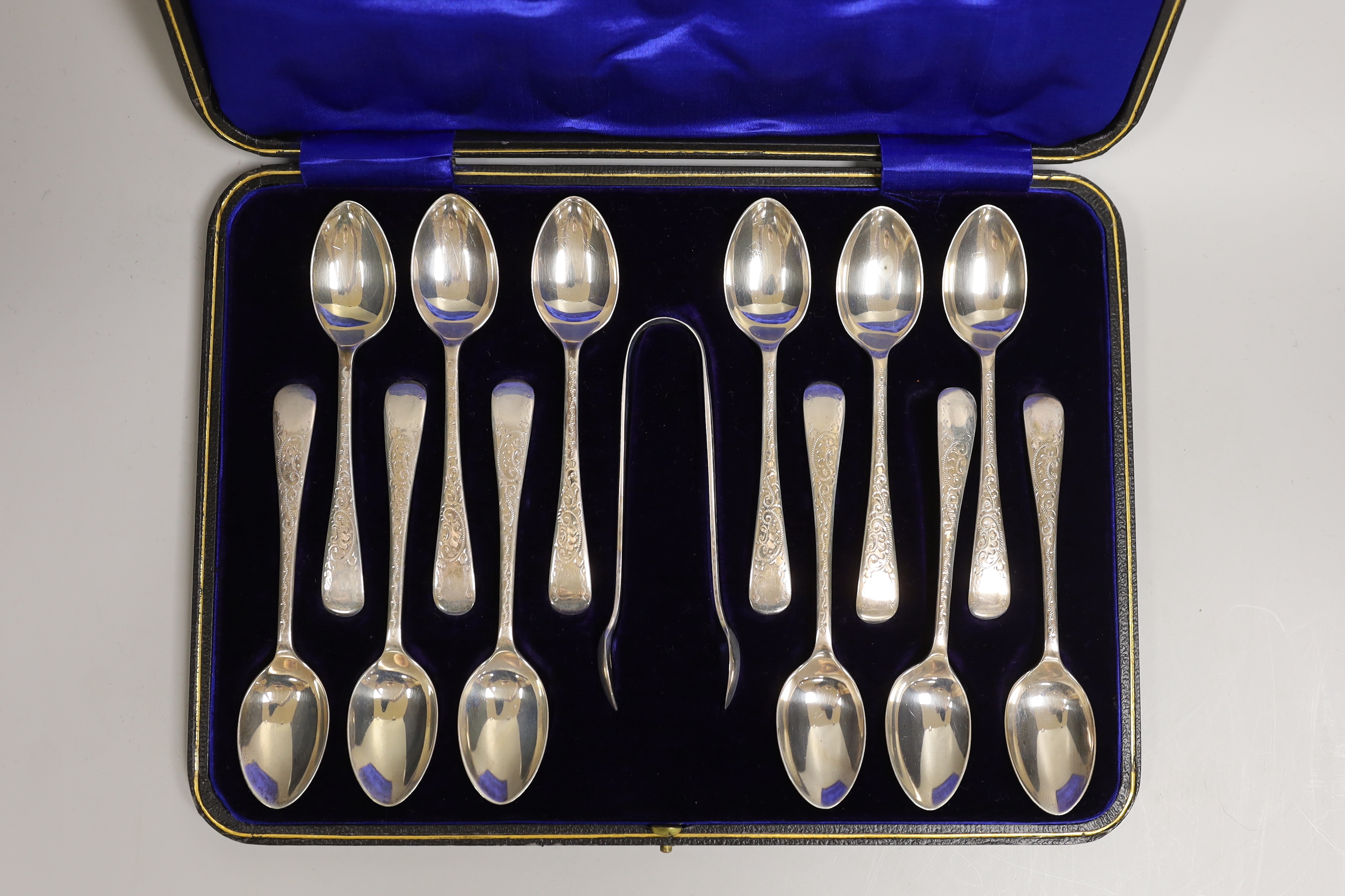 A cased set of twelve George V engraved silver Old English pattern teaspoons and pair of sugar tongs, W.S. Savage & Co, Sheffield, 1914.